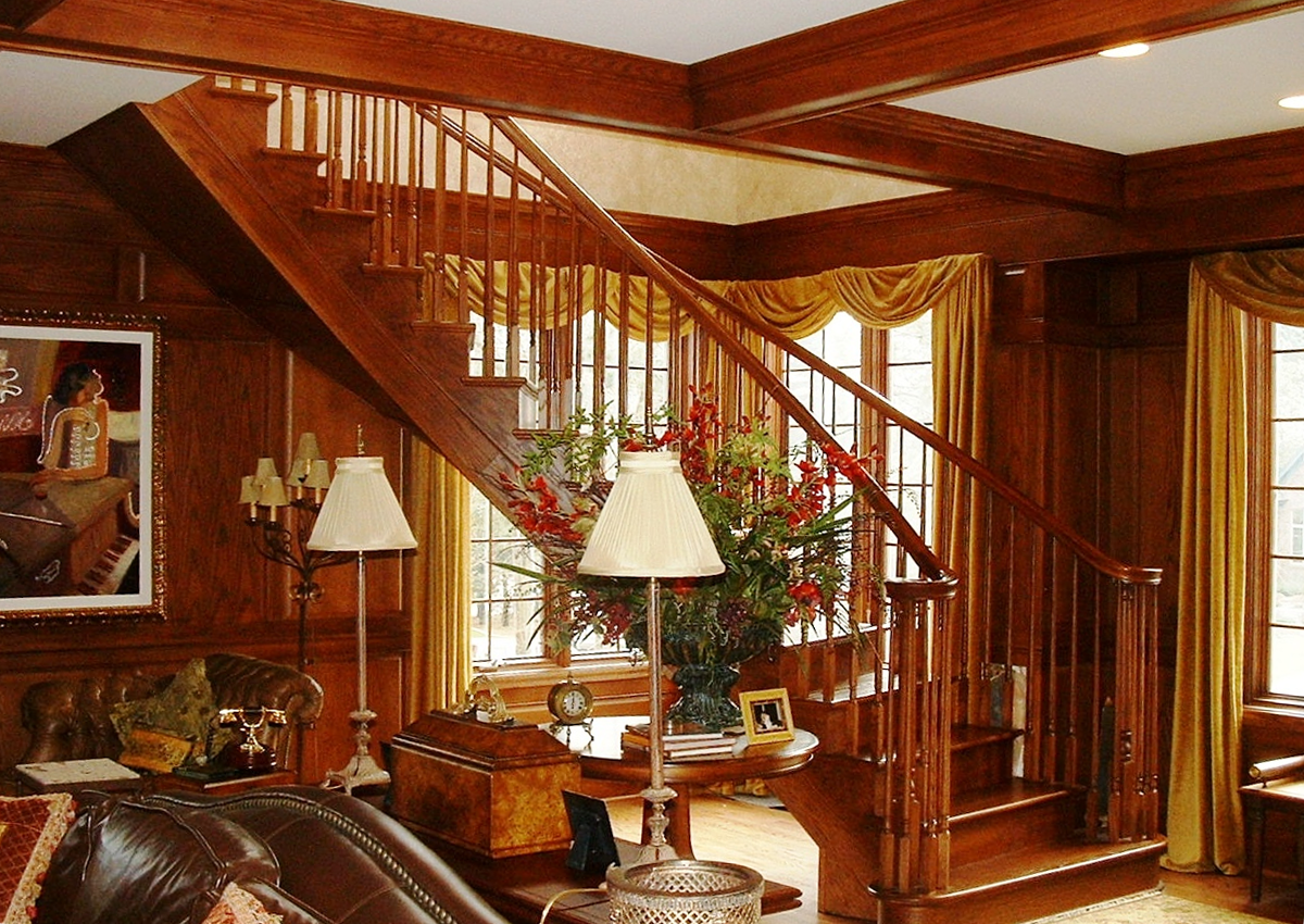Wooden staircase in a well-lit interior, with ornate details, leading upward.