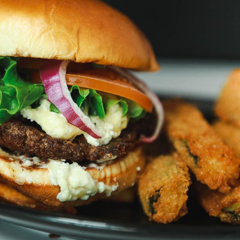 Burger on bun with lettuce, tomato, and onion; served with fried pickles.