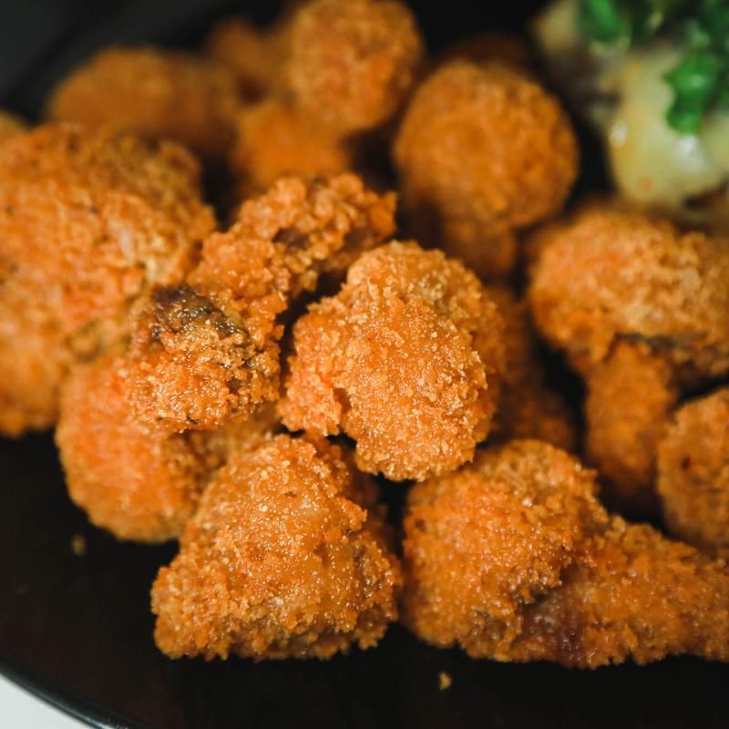 Crispy, breaded mushrooms on a black plate, close-up shot.
