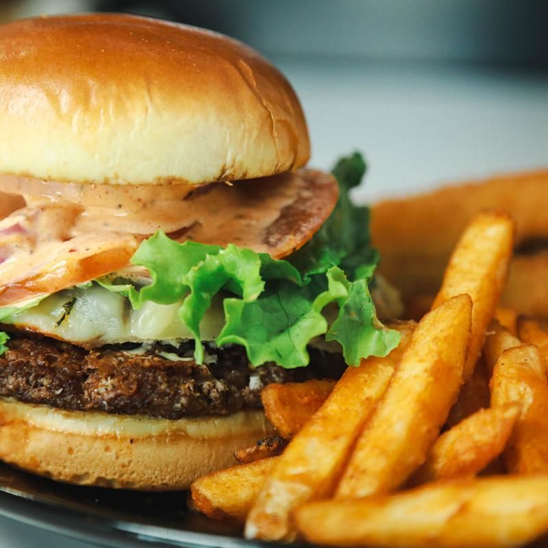 Hamburger with lettuce, tomato, and sauce, served with fries.
