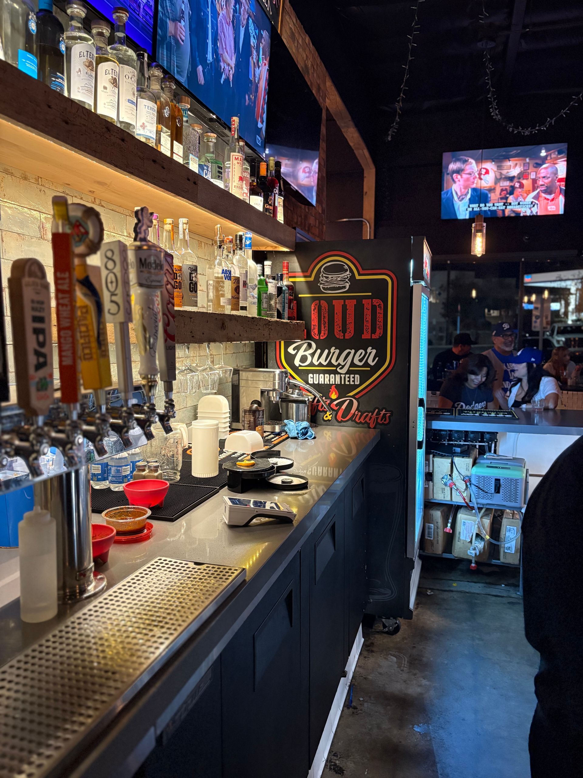Bar interior with taps, liquor bottles on shelves, and a