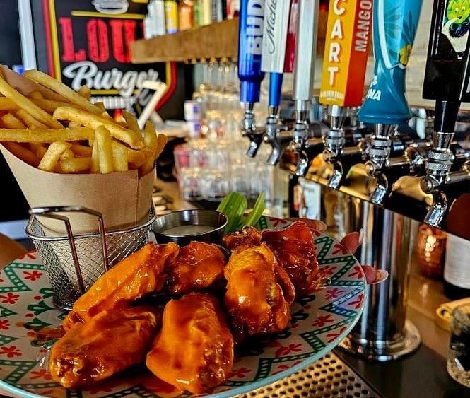 Chicken wings, fries, and beer taps at a bar.