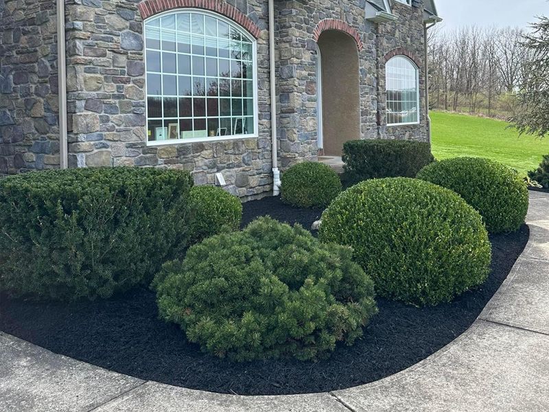 A stone house with a lush green garden in front of it.