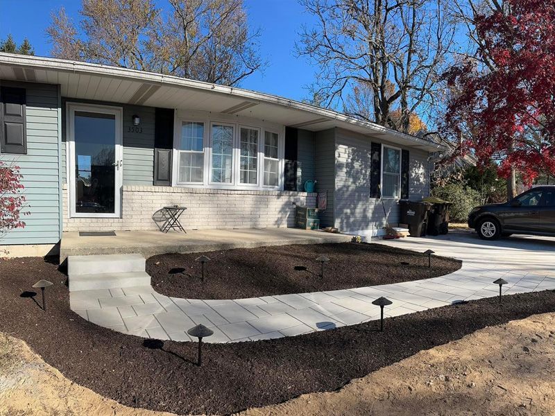 A house with a concrete walkway and a car parked in front of it.