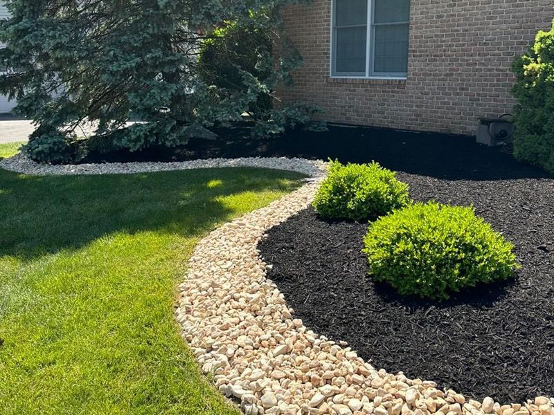 A brick house with a lush green lawn and a stone walkway leading to it.