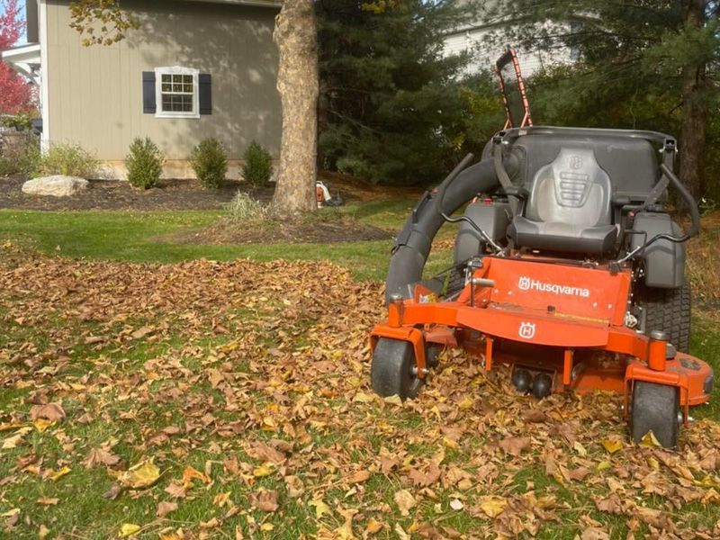 A husqvarna lawn mower is covered in leaves