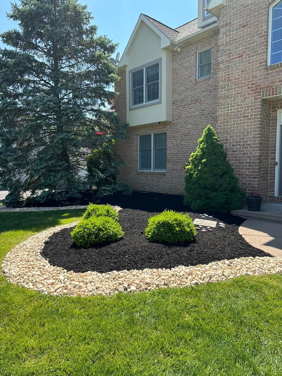 A large brick house with a lush green lawn in front of it.