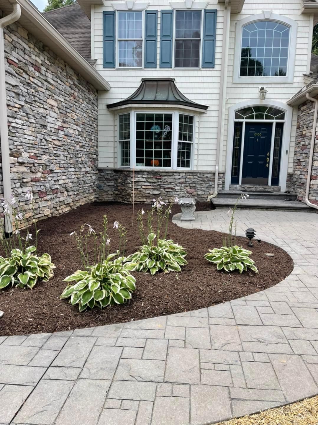 A house with a stone wall and a patio in front of it.