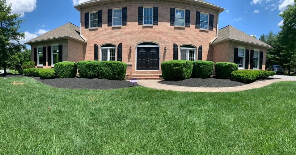 A large brick house with a lush green lawn in front of it.
