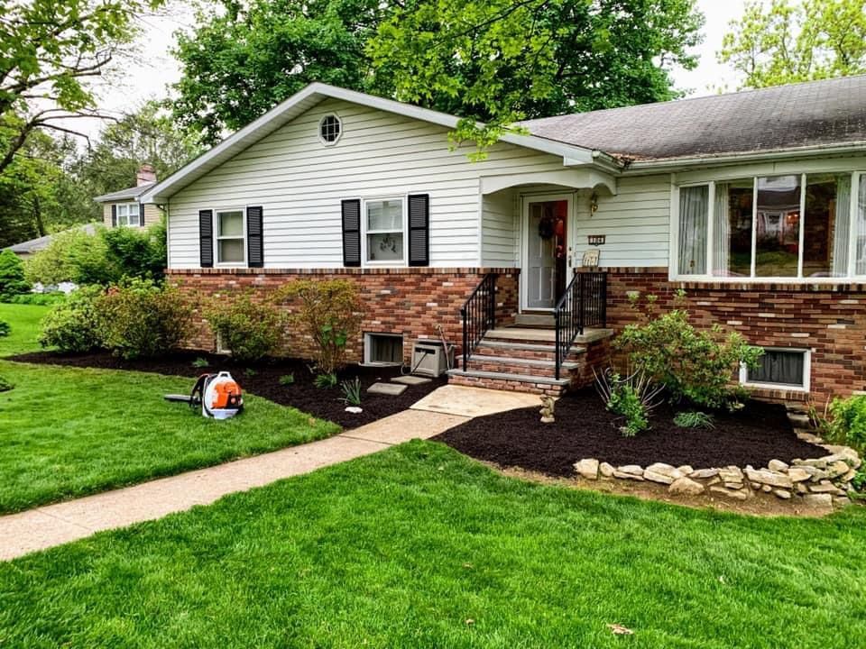 A white house with a brick wall and a lush green lawn.