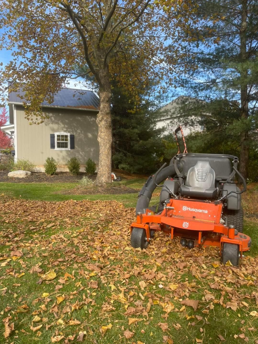 A lawn mower is sitting on top of a lush green lawn covered in leaves.