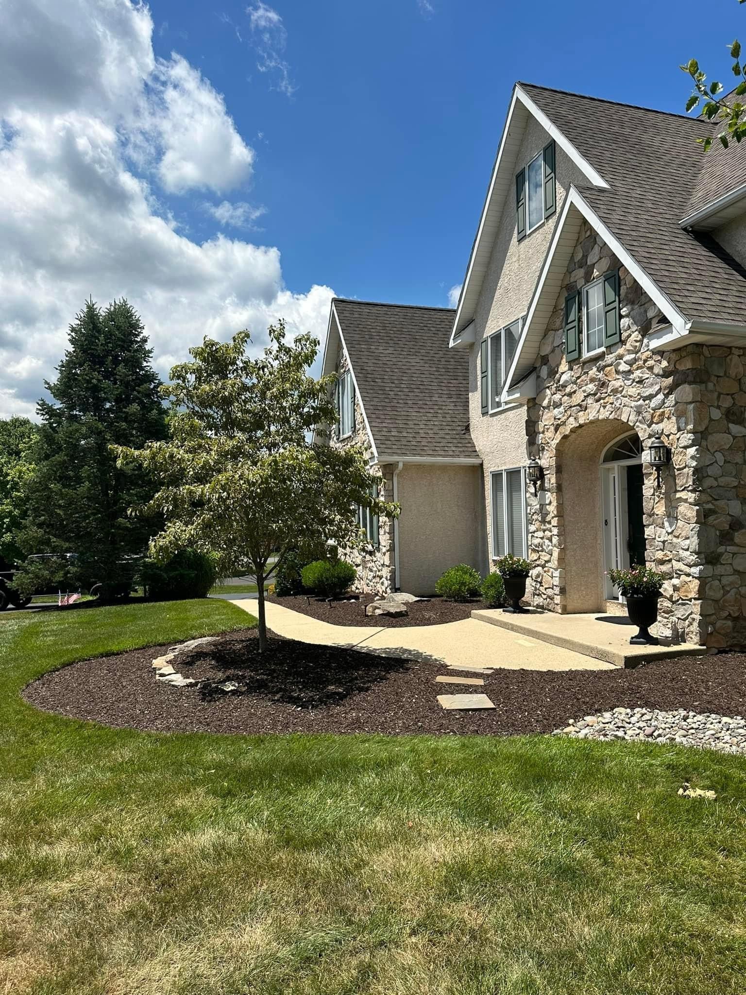 A large house with a lush green lawn in front of it on a sunny day.