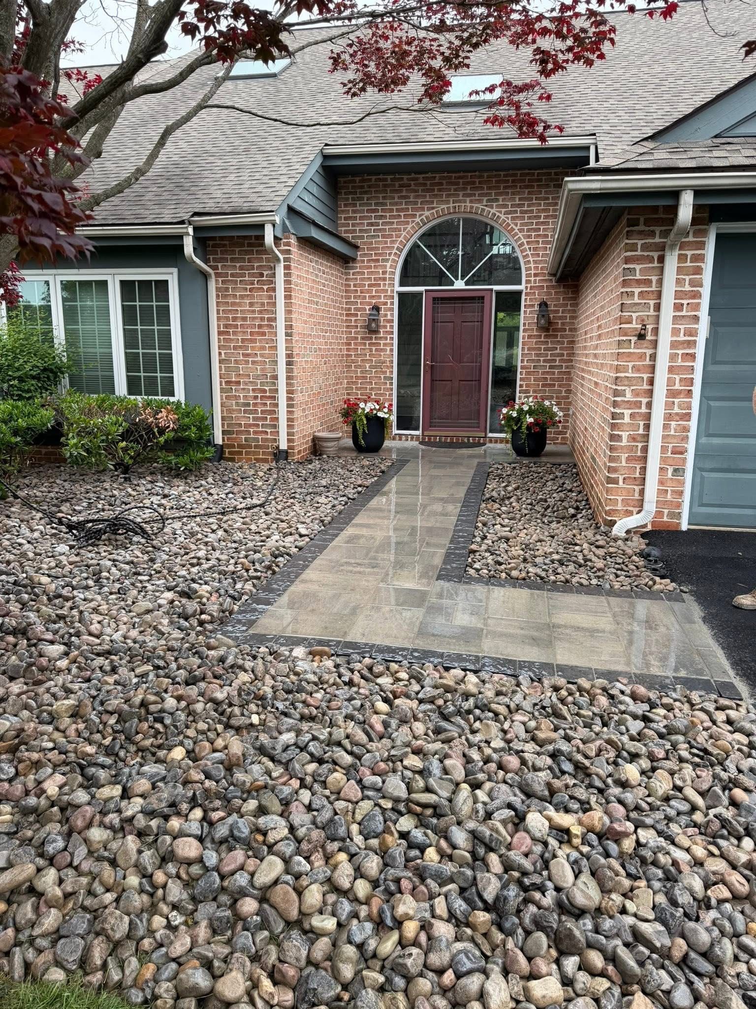 Brick house entrance with gray stone path and pebbled front yard