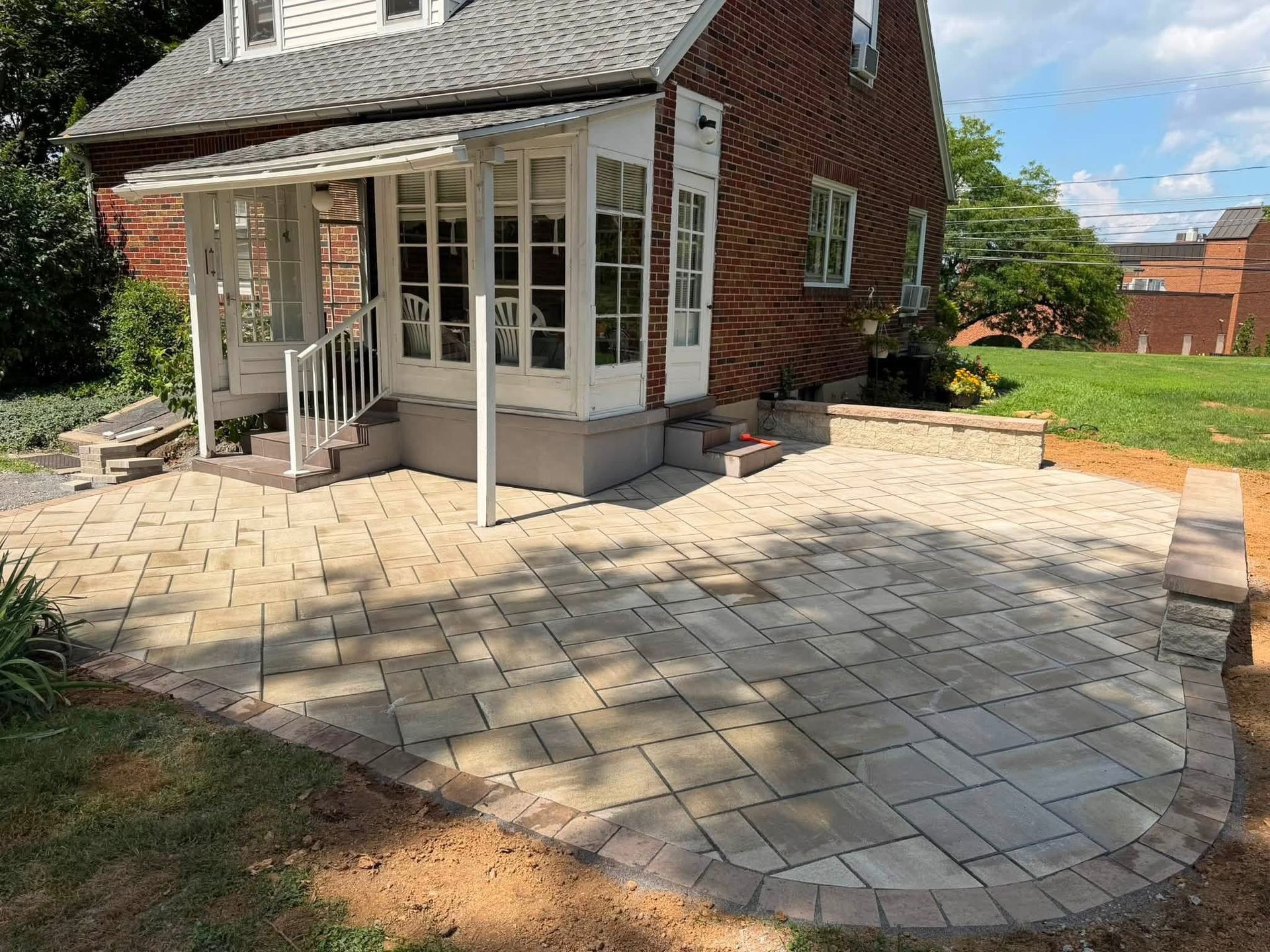 Brick house with a glass porch and a paved stone patio in the front yard