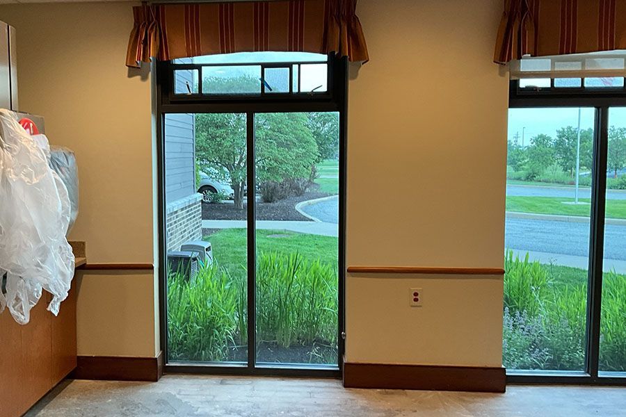 A room with a lot of windows and a white dress hanging on the wall.