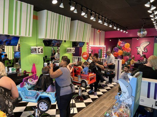 A group of people are getting their hair cut at a barber shop.