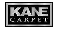 The kane carpet logo is a silver logo on a black background.