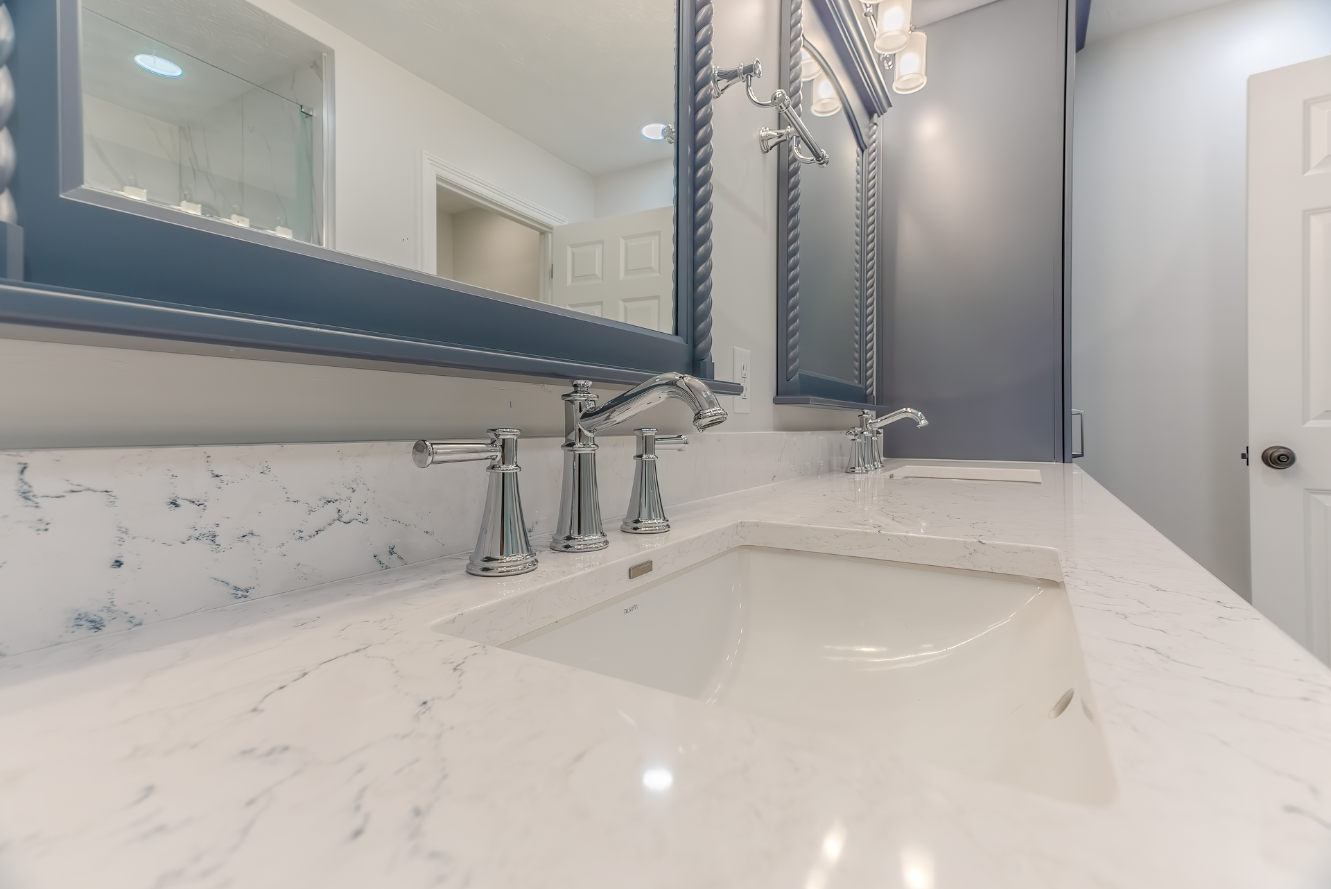 Bathroom with white countertops, two sinks, and large mirrors. Gray and white color scheme.