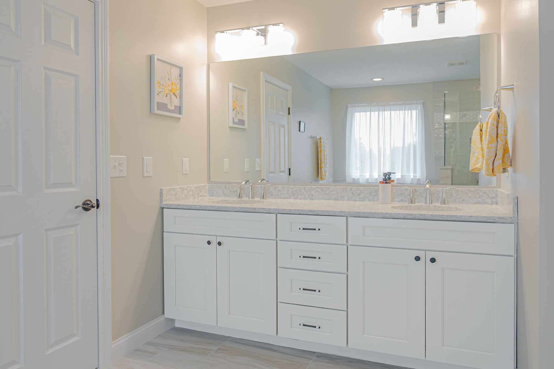 White bathroom with double vanity, large mirror, and neutral tones.