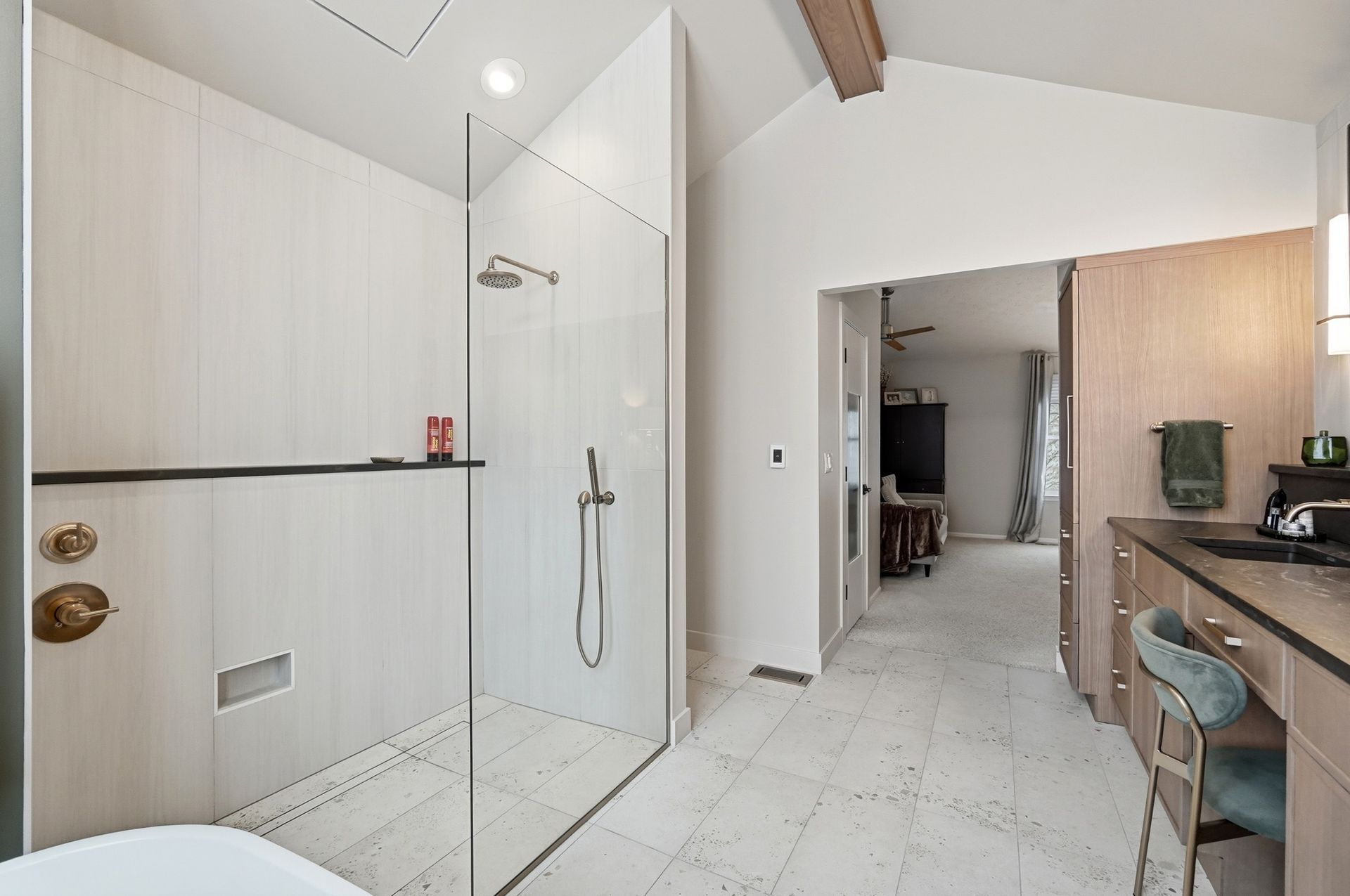 Modern bathroom with glass shower, light-colored walls, and a vanity on the right.