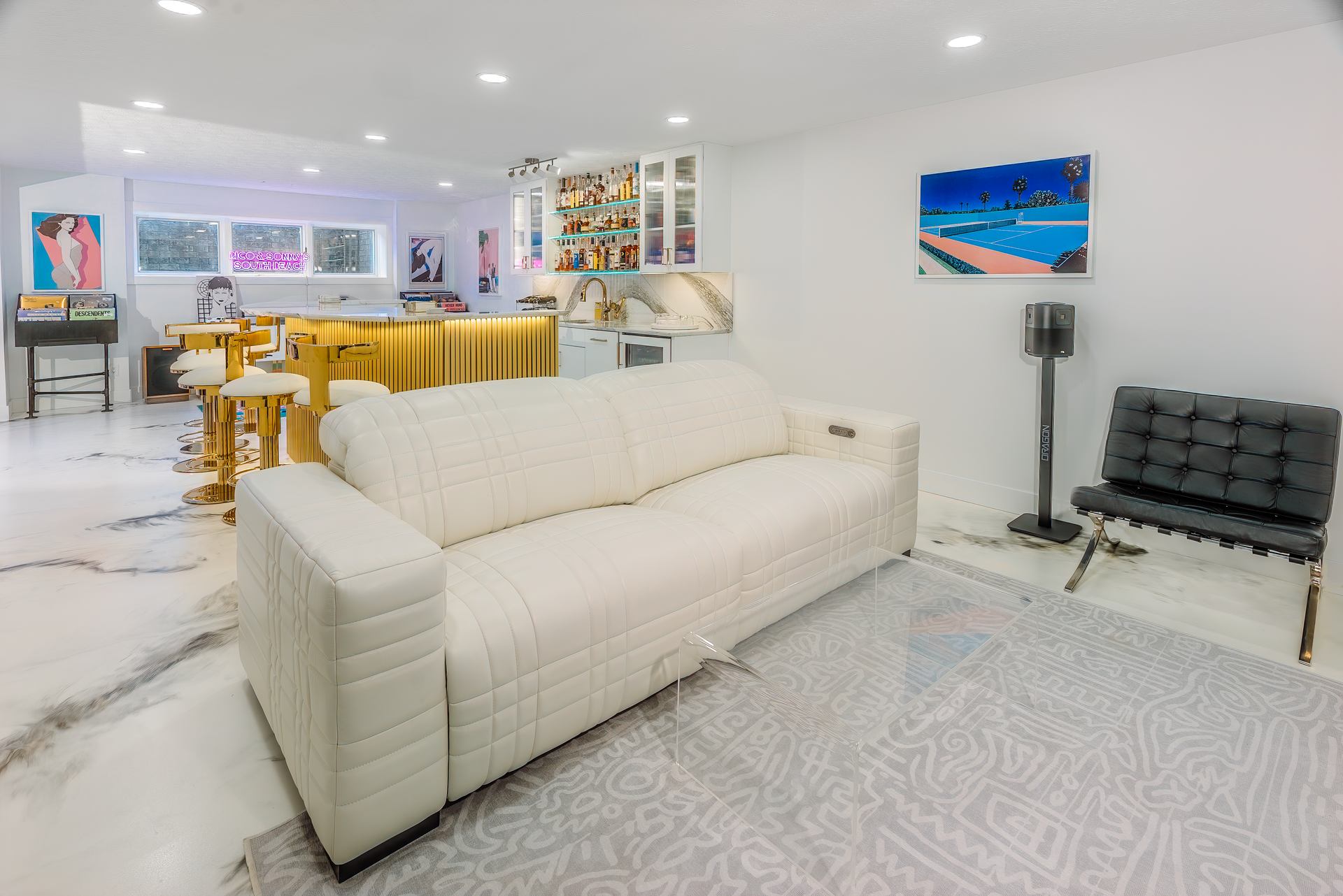 White modern living room with a couch, art, and a bar.