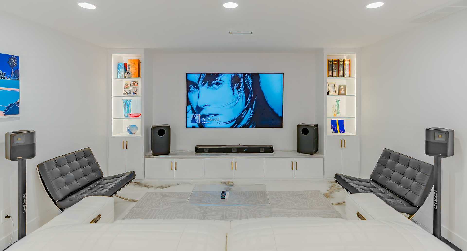 Home theater room with a large screen, speakers, seating, and built-in shelves.