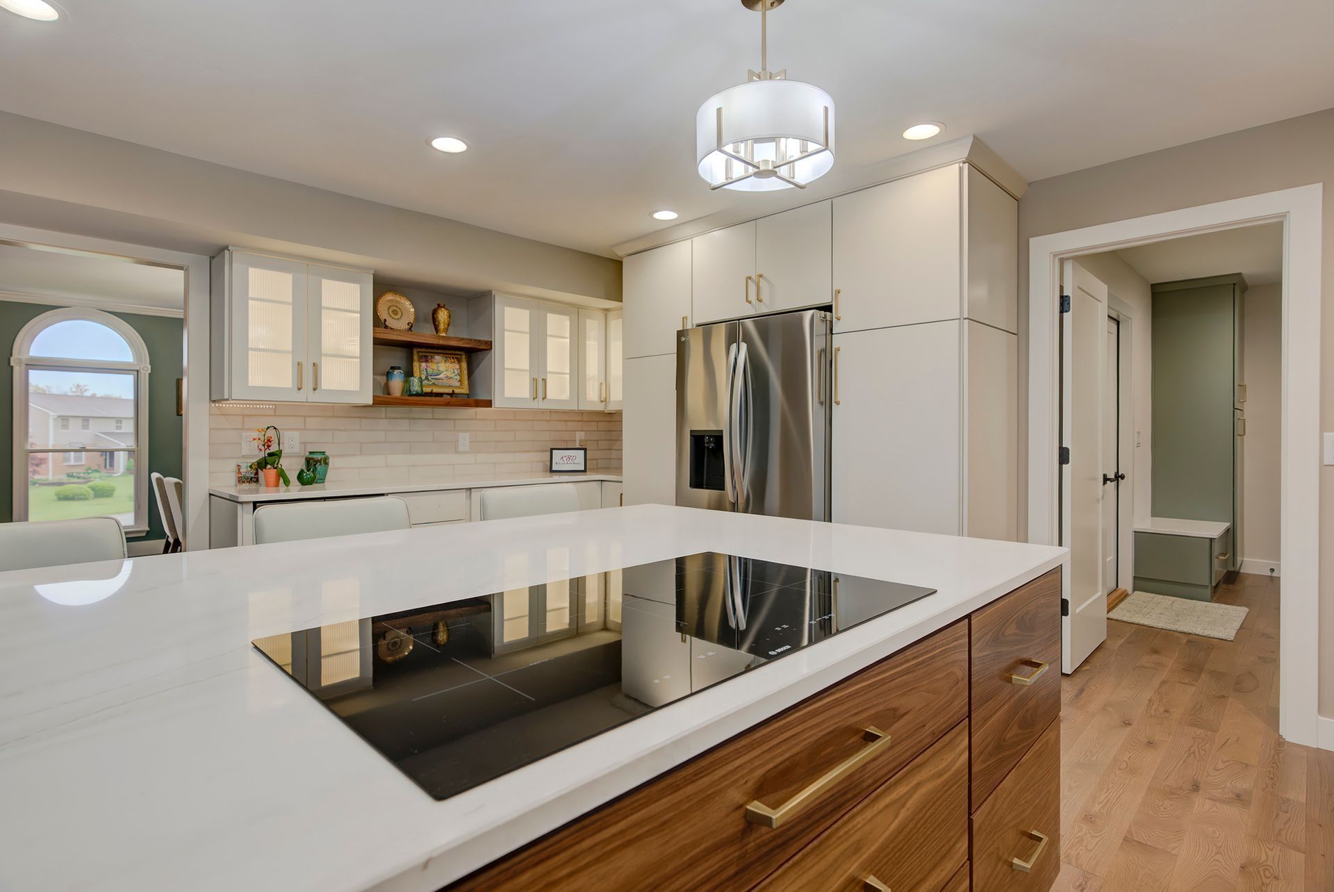 Modern kitchen with white countertops, stainless steel appliances, and wooden accents.