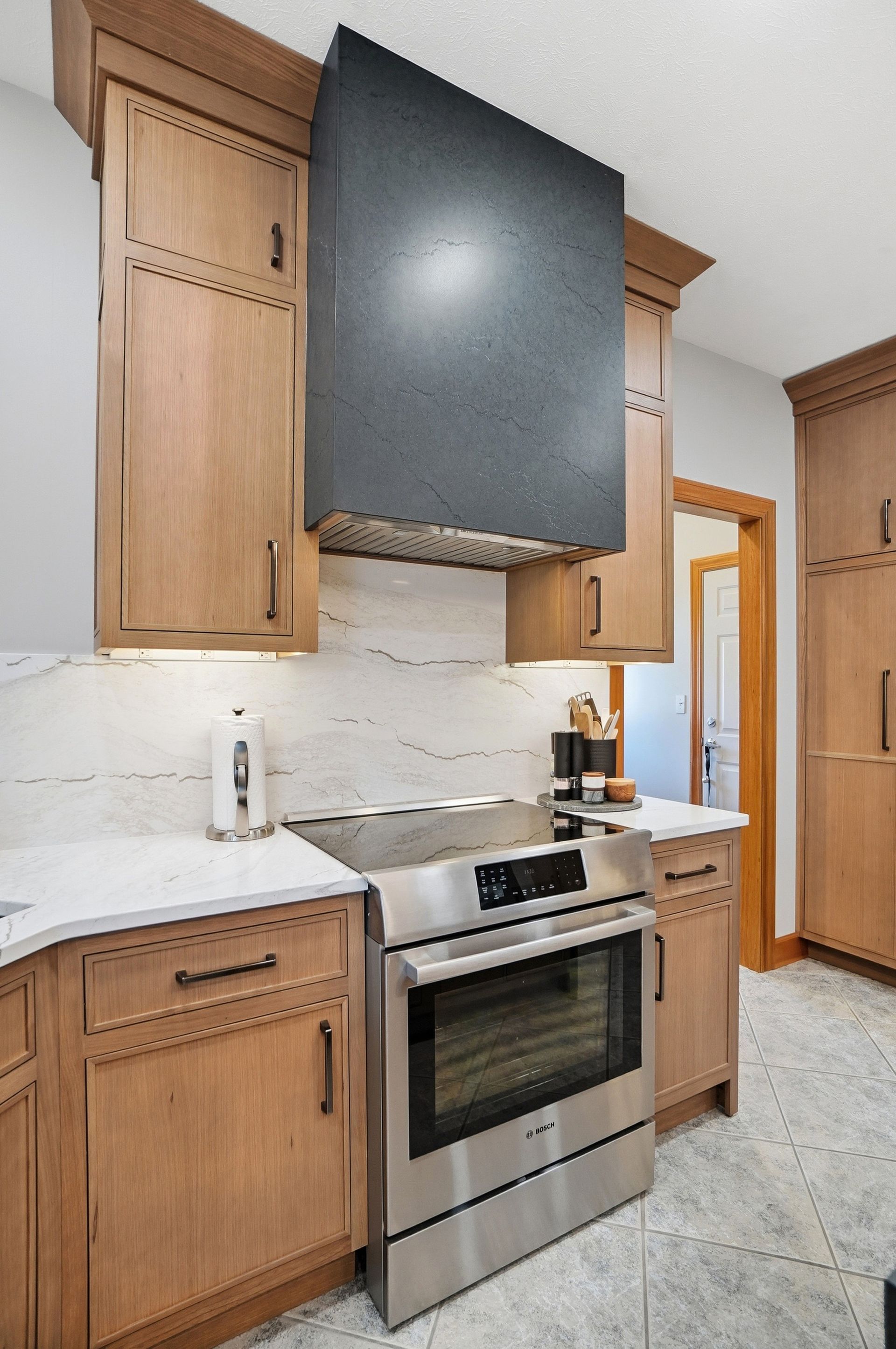 Stainless steel oven in kitchen with wood cabinets and a dark range hood.
