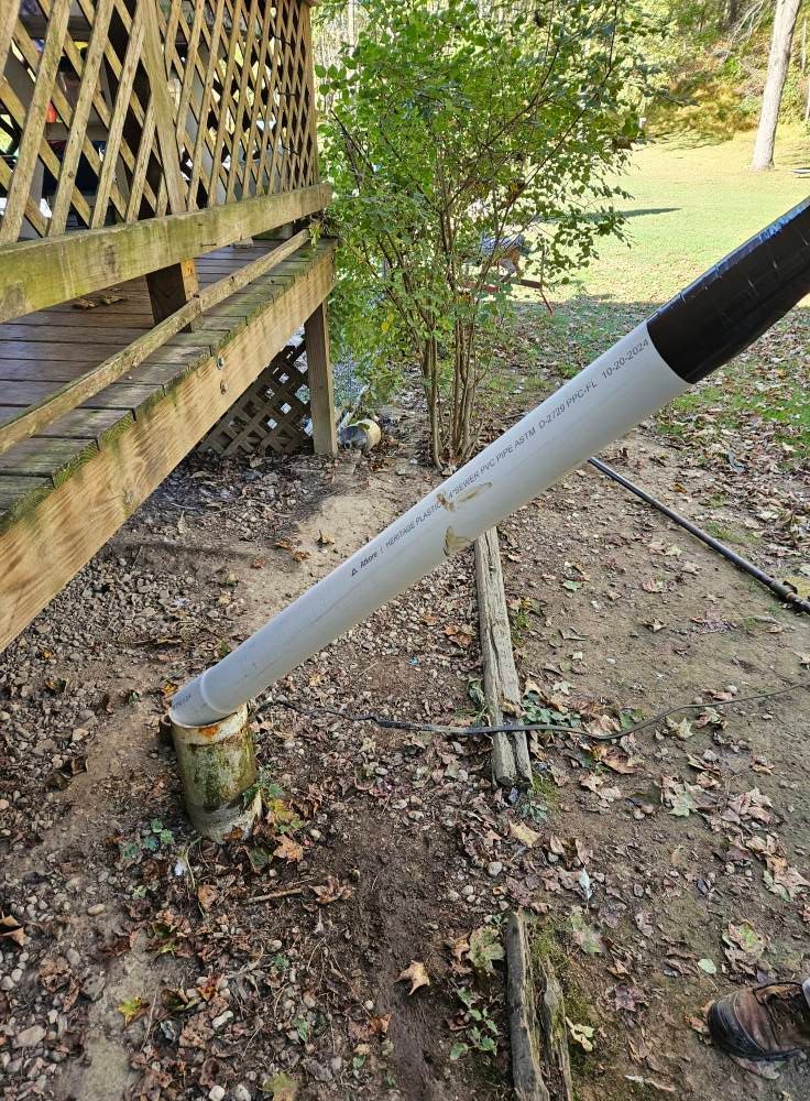 PVC pipe resting on a tree stump, angled toward a deck.