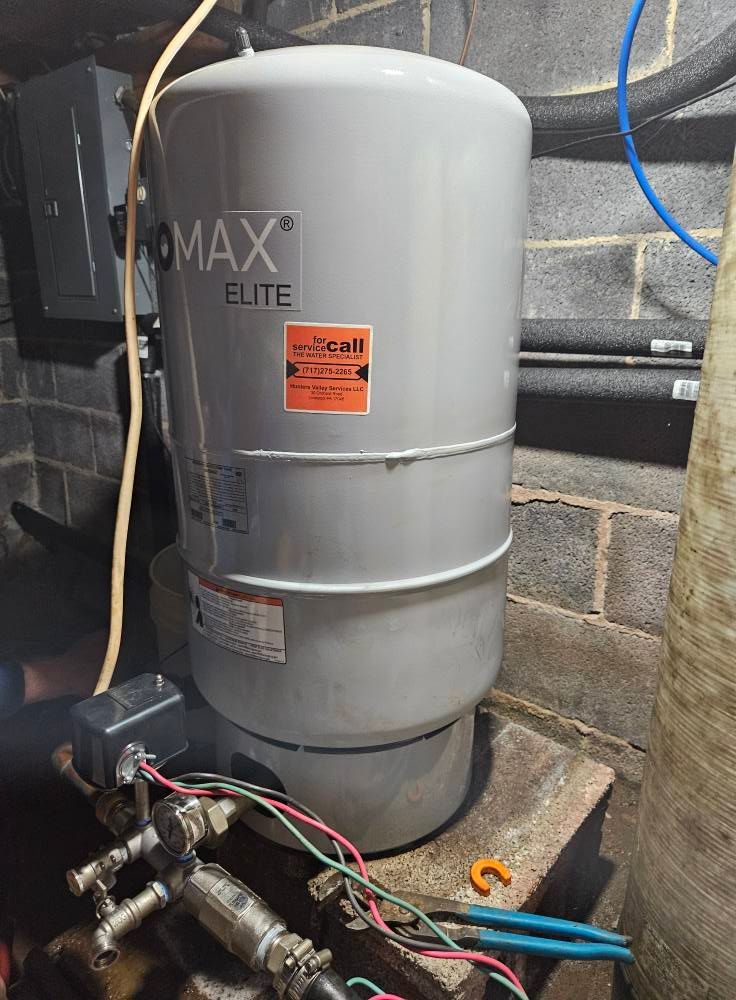 A well pressure tank in a basement setting, connected to pipes and electrical components.