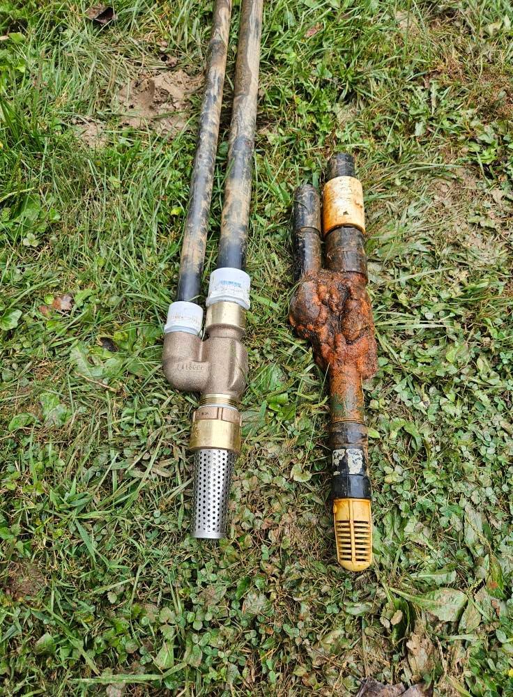 Two well water pump assemblies on green grass, one new, one rusty and old.