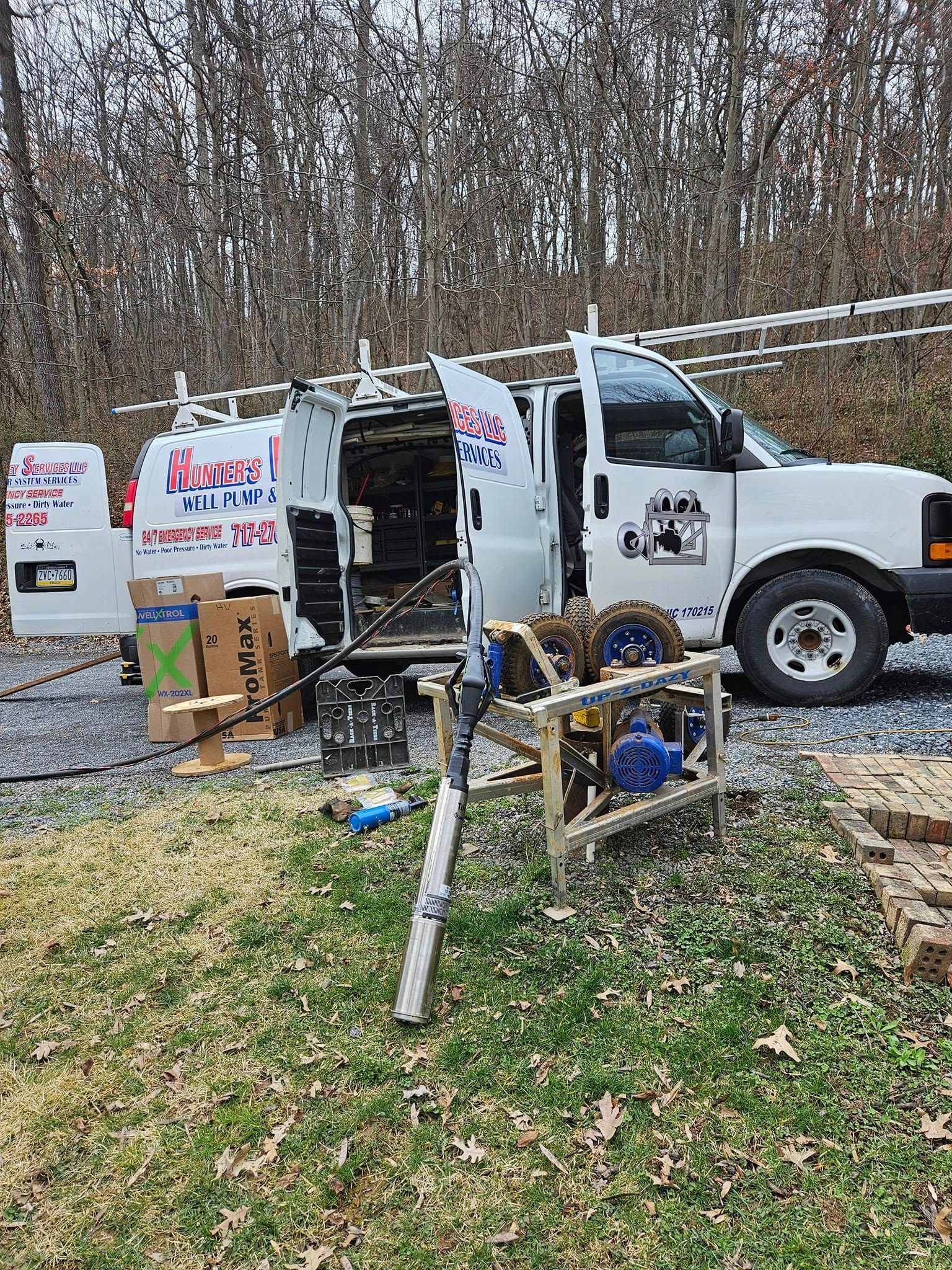 White work van with open doors and equipment in a yard setting.