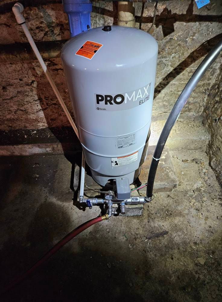 Gray well water pressure tank in a basement setting with various connected pipes and a blue filter.