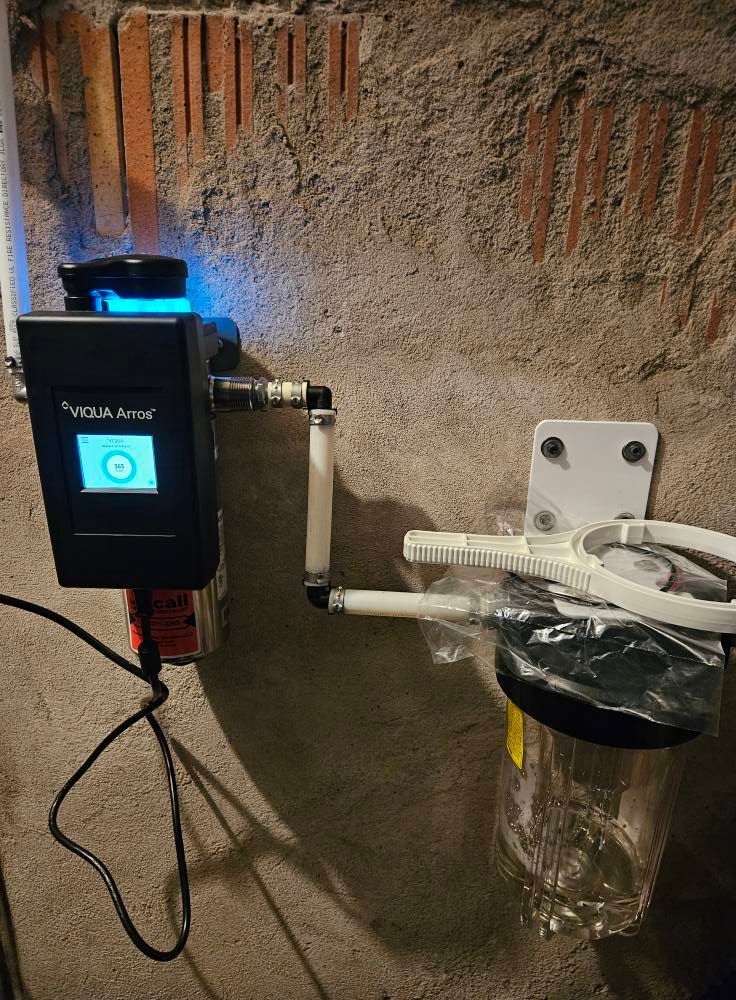 Water filter system mounted on a brick and concrete wall. 