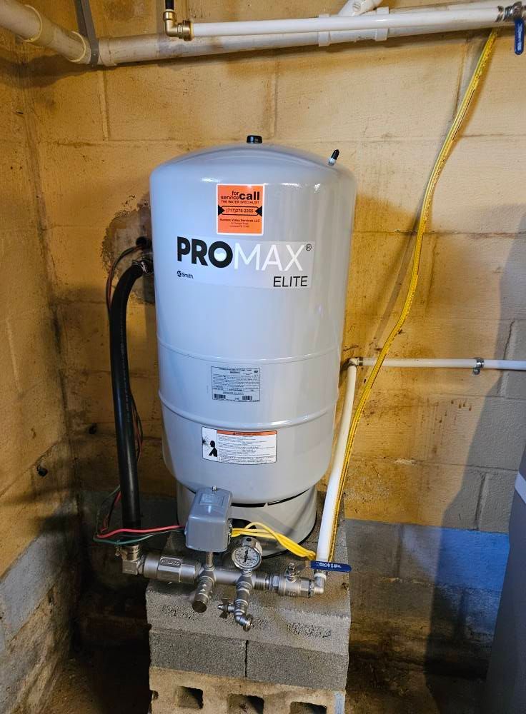 Gray water pressure tank on cinder blocks in a basement.
