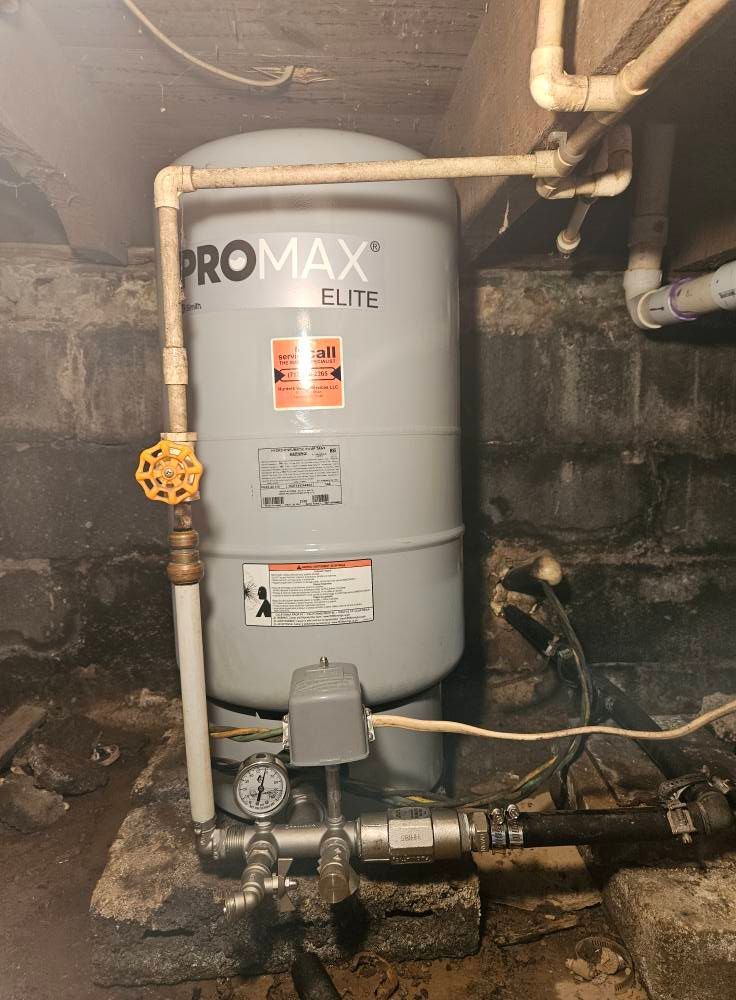 Water pressure tank in a basement, with plumbing and pressure gauge.