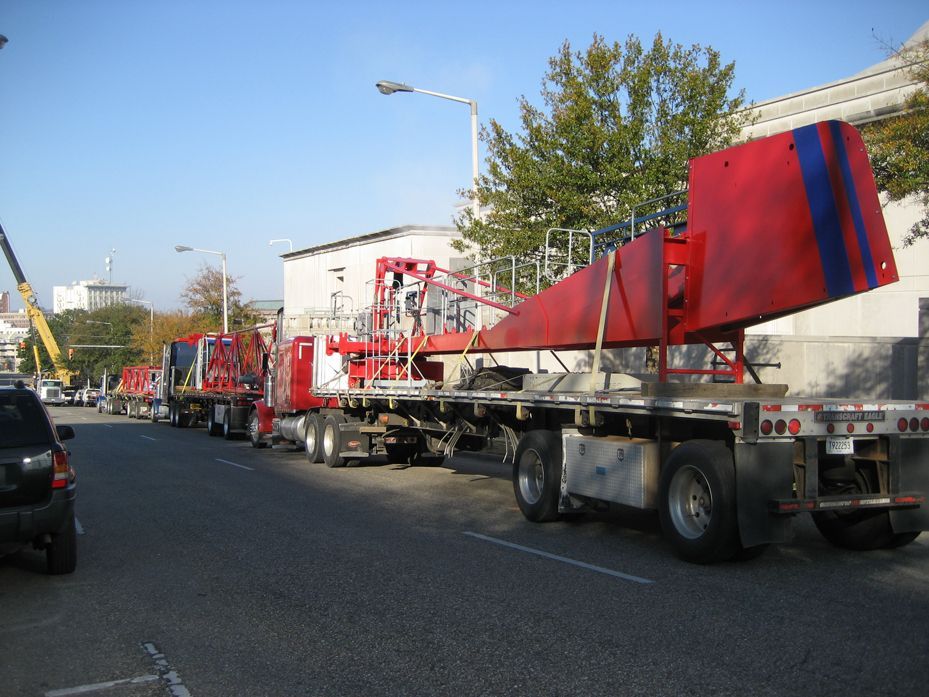 A row of red trucks are parked on the side of the road