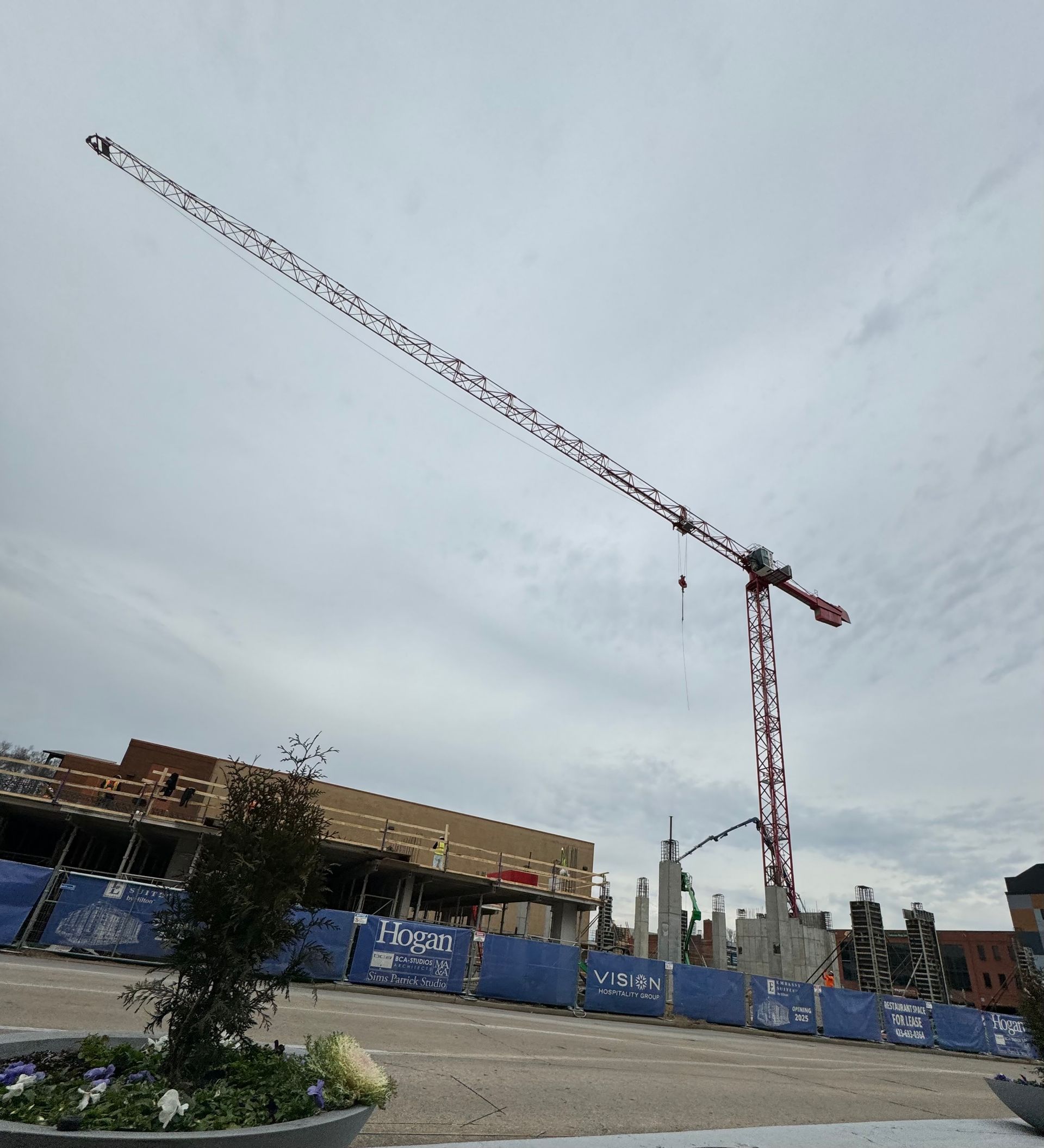 A large crane is flying over a construction site
