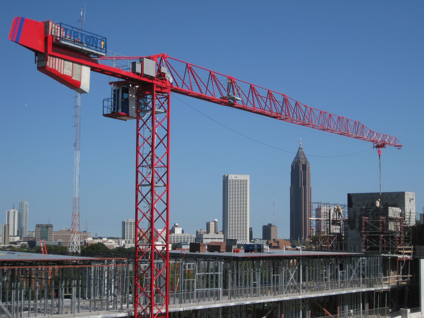 A red and white construction crane is in front of a city skyline
