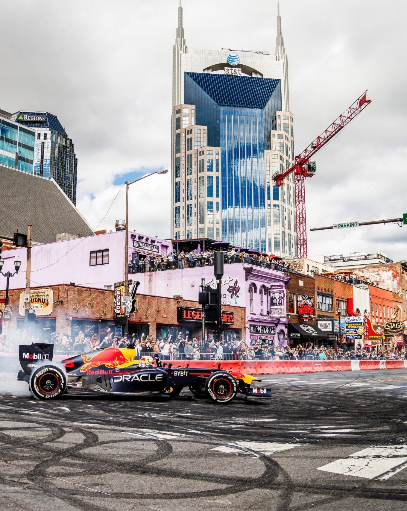 A red bull race car is driving down a city street