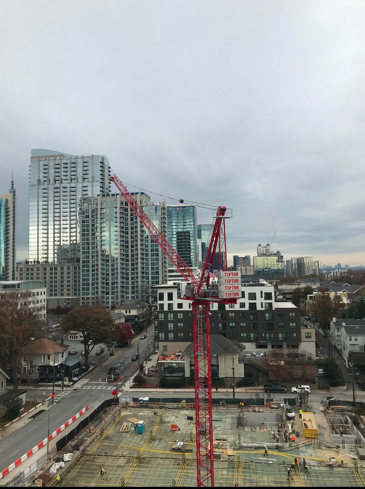 An aerial view of a construction site with a red crane in the foreground