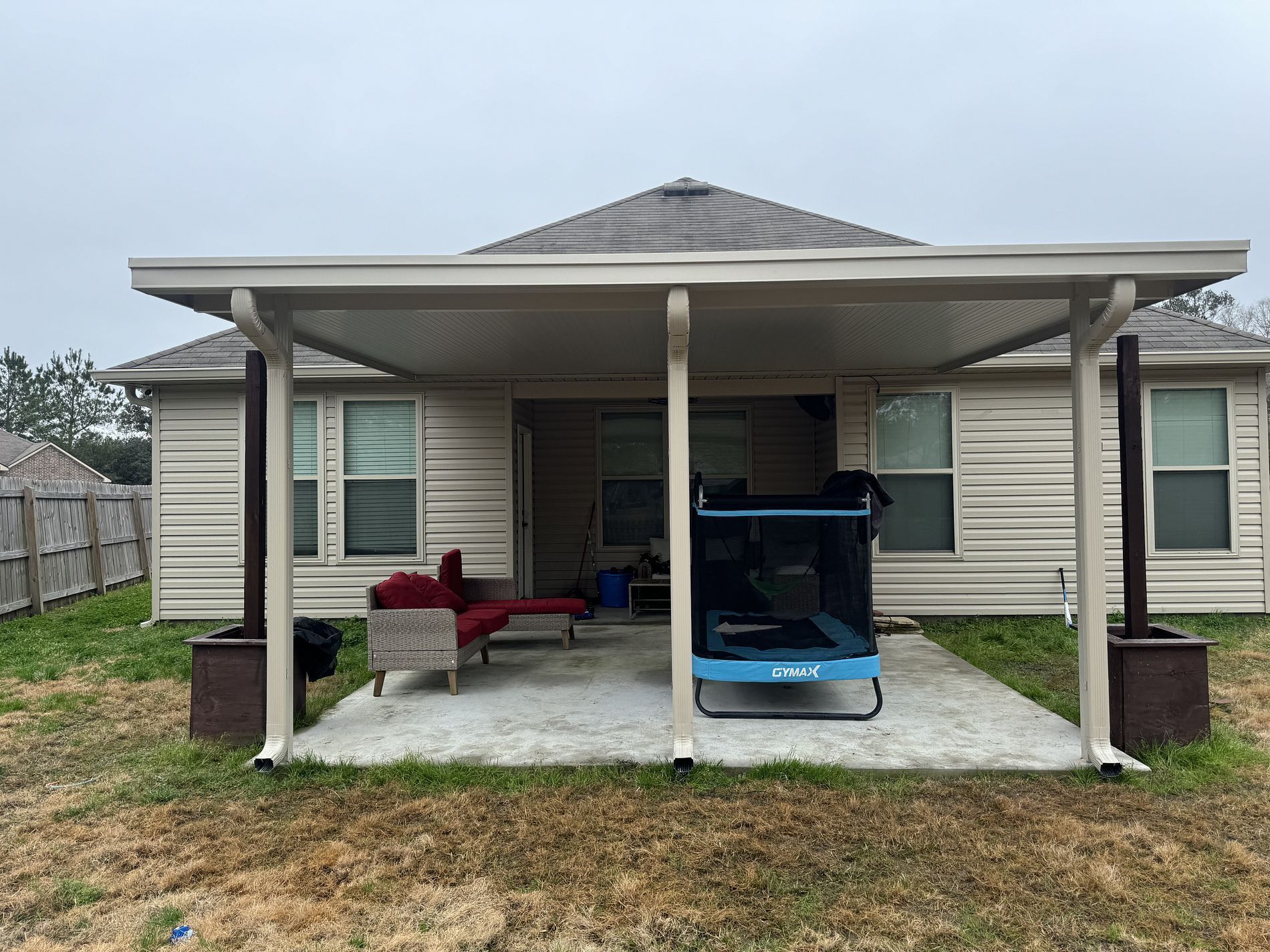 Backyard patio with an attached roof, furniture, and a small trampoline. The home exterior is visible in the background.