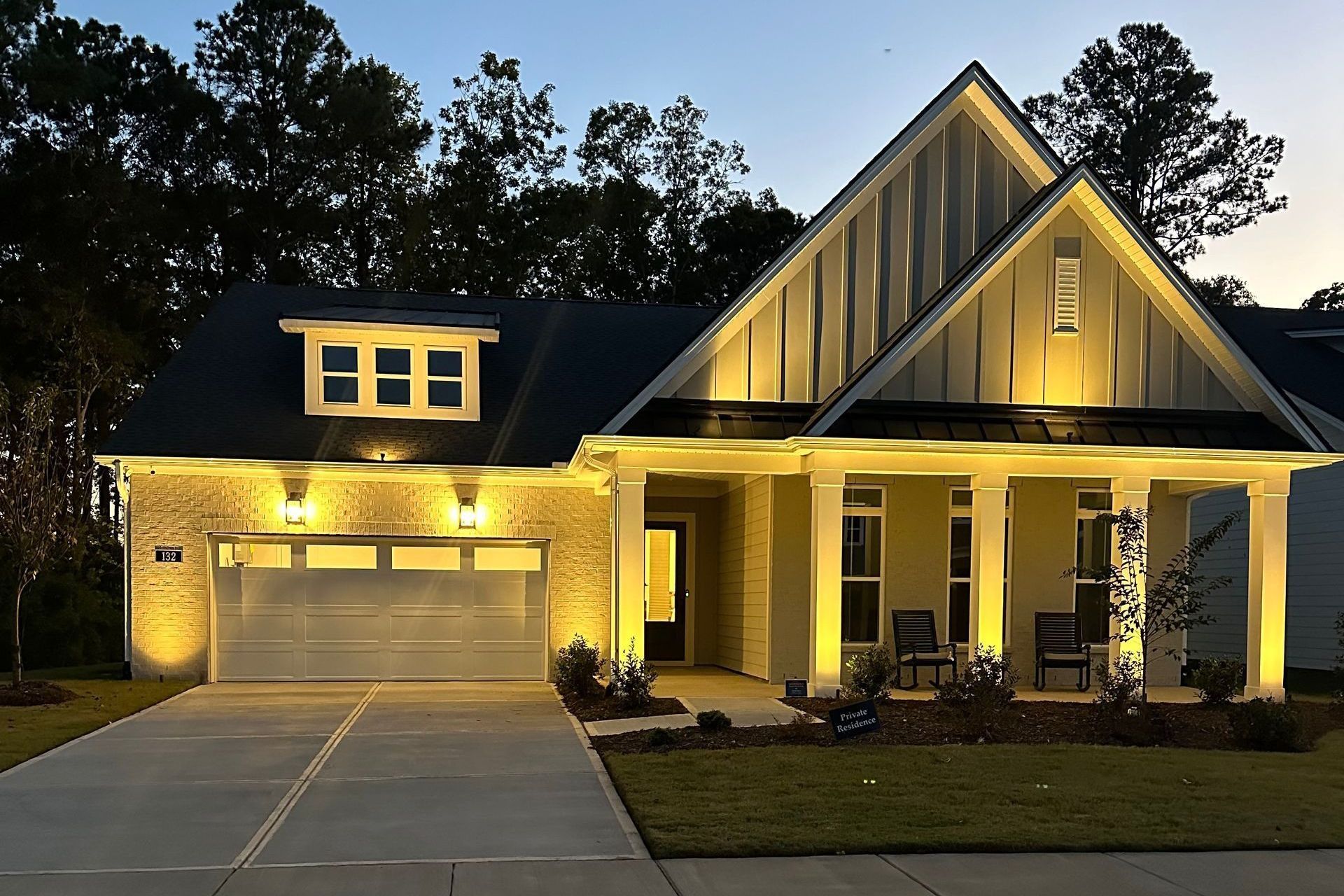 Illuminated suburban house with a two-car garage at dusk