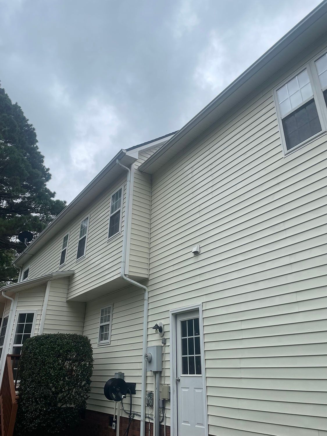 Beige two-story townhouse exterior with white trim and a cloudy sky