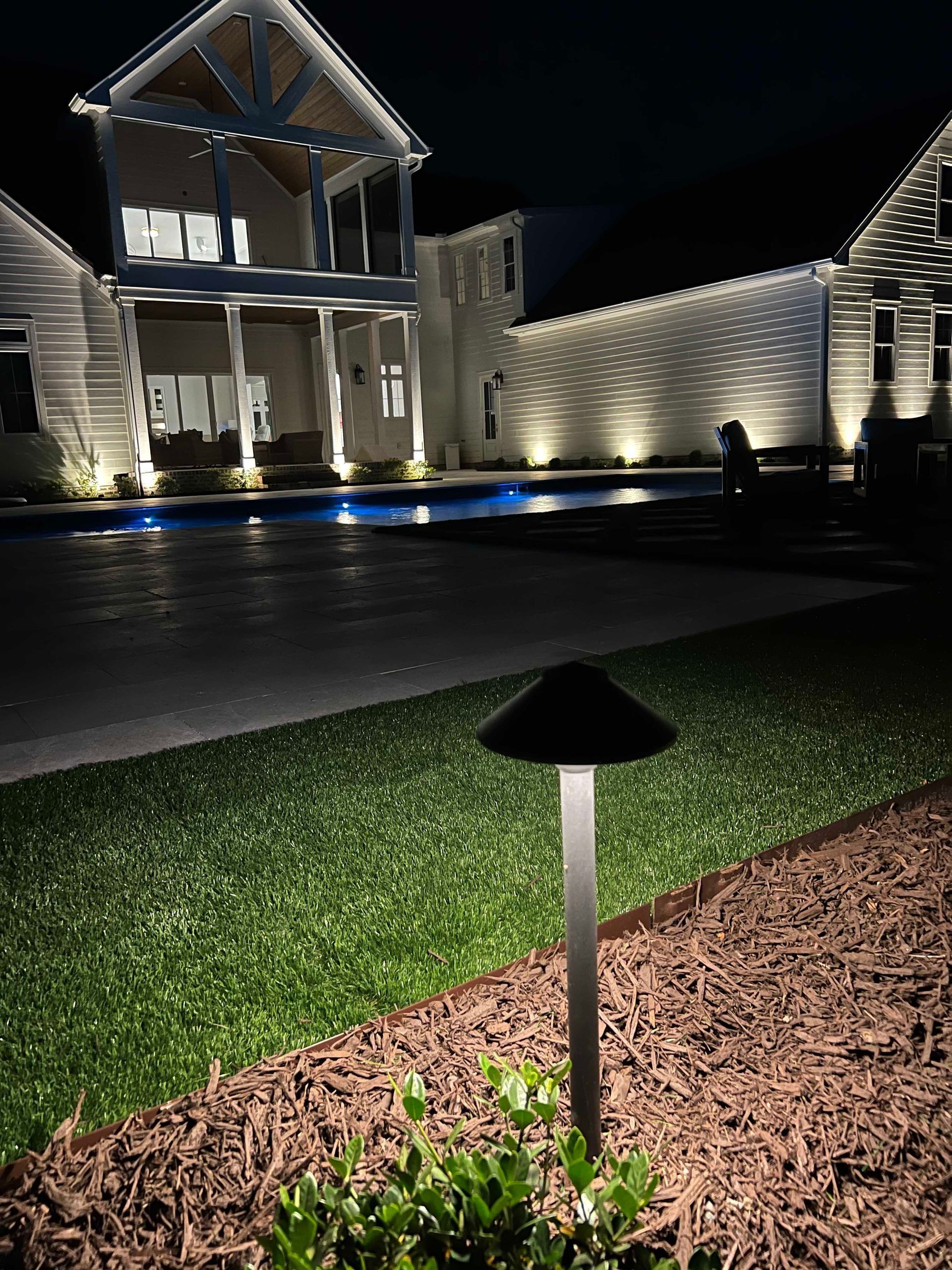 Nighttime view of a lit modern building with landscaped lawn and pathway lights