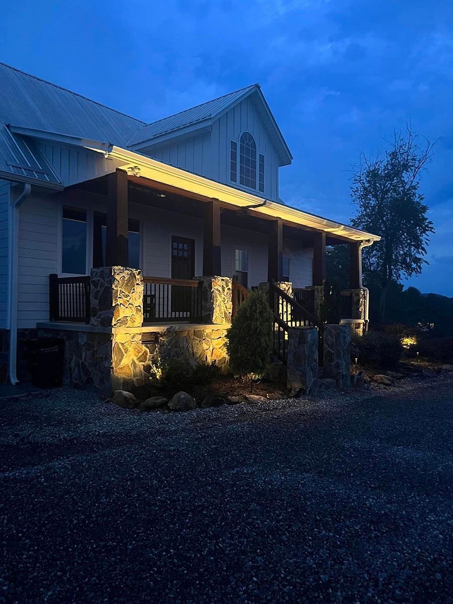 House porch at dusk with warm yellow lights and a dark, cloudy blue sky