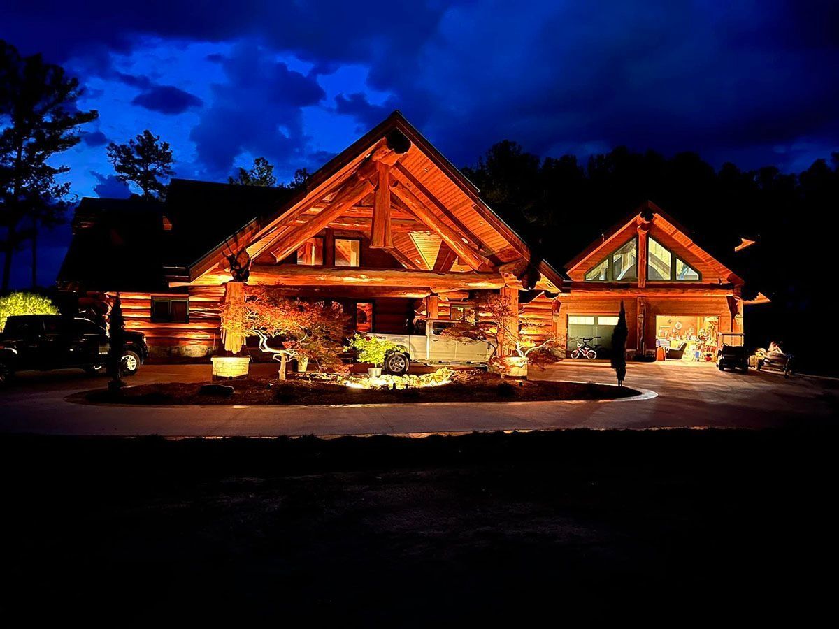 Illuminated log cabin at night with warm orange lights against a dark blue sky