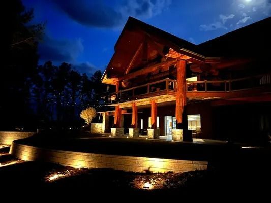 Illuminated wooden lodge at night with warm lights and a blue sky backdrop