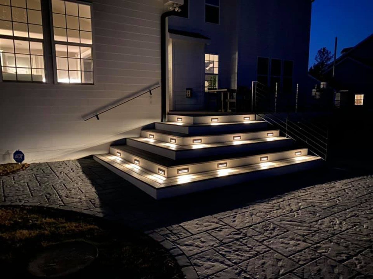 Illuminated front steps and entryway of a house at night with warm lights along the stairs