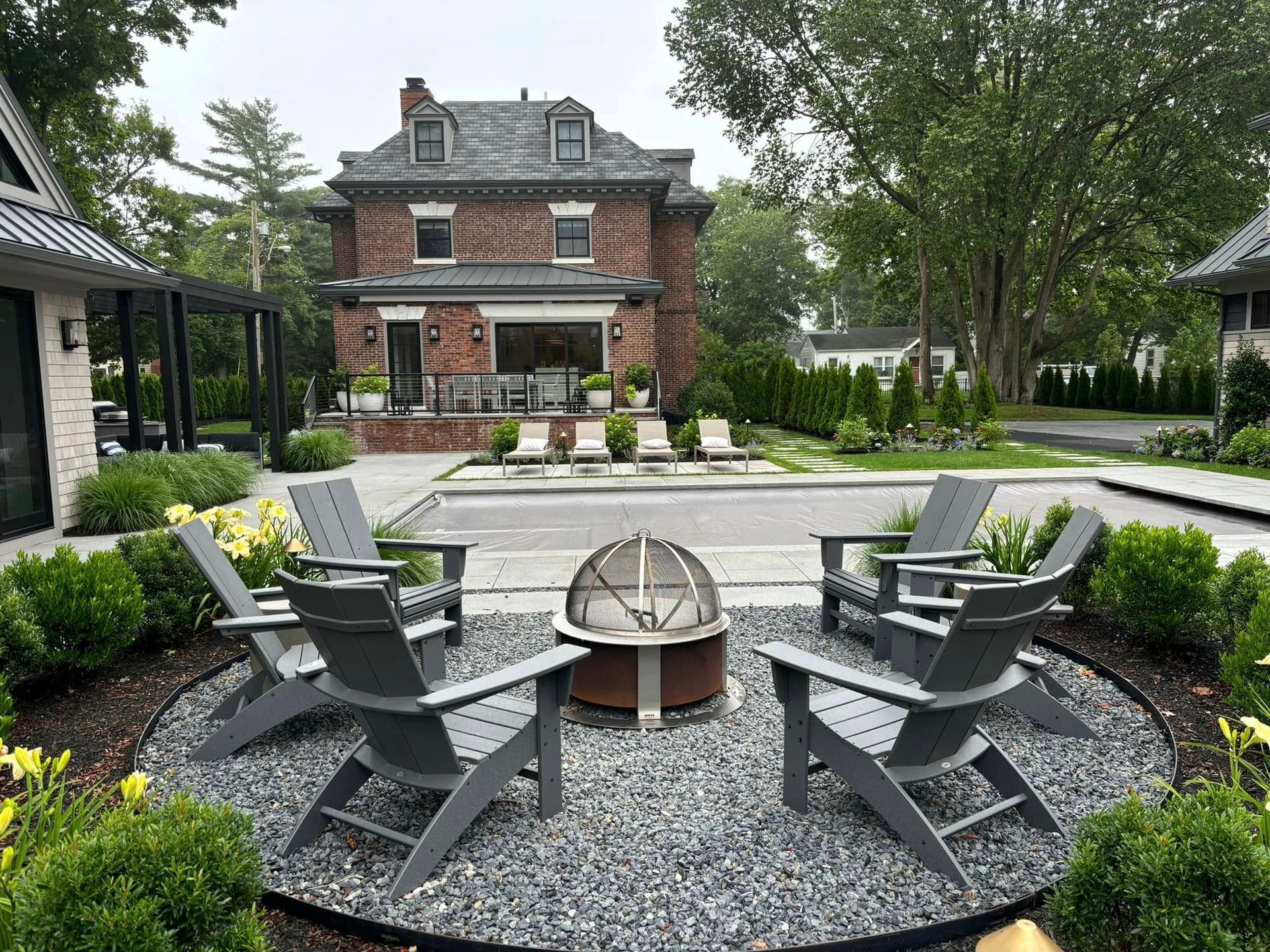 There is a fire pit in the middle of the patio with chairs around it.